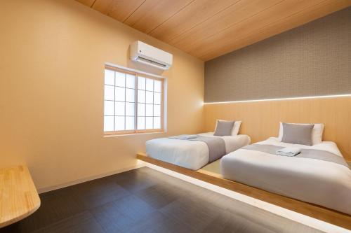 two beds in a room with a window at 明月荘鶴橋Moon villa in Osaka