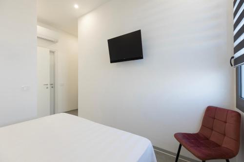 a bedroom with a white bed and a red chair at Associazione Garage24 Aps Ets in Portoferraio