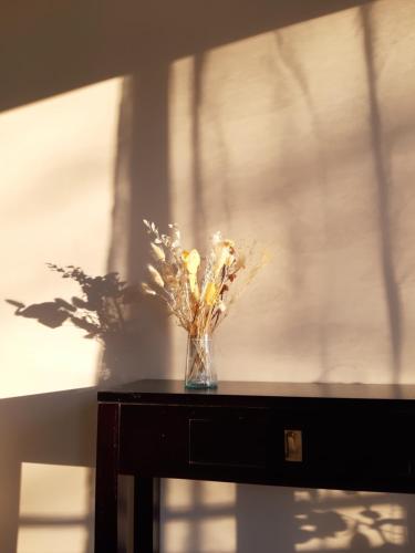 un vase de fleurs assis sur une table dans l'établissement Le Cèdre, appartement avec garage, à Vaison-la-Romaine