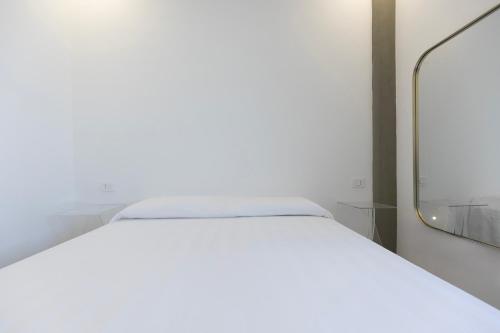 a white bed in a room with a mirror at Associazione Garage24 Aps Ets in Portoferraio