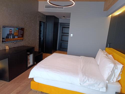 a bedroom with a white bed and a flat screen tv at Toka Hotel Restaurant in Pogradec