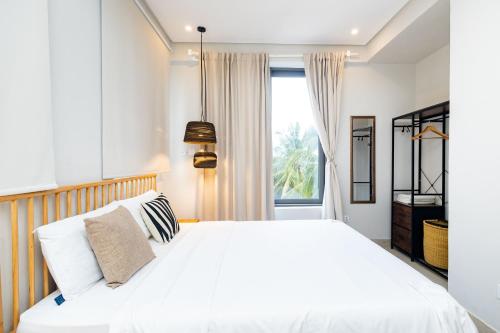 a bedroom with a white bed and a window at Serenity Residences & Spa - Kokrobite Beach in Kokrobite