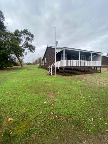 a building with a large grass field in front of it at Emu Cottage in Deeside