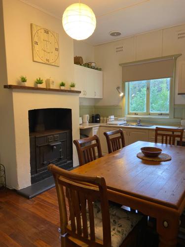 a kitchen with a wooden table and a clock on the wall at Emu Cottage in Deeside