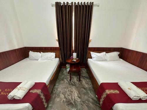 two twin beds in a room with a table at Nha Trang Homestay Đồng Nai in Tân Phú