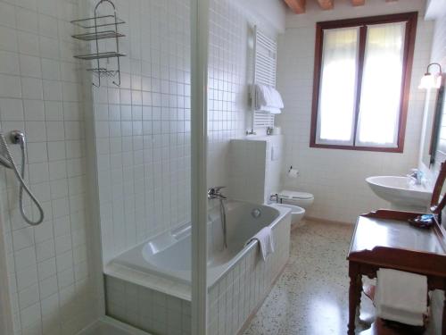 La salle de bains blanche est pourvue d'une baignoire et d'un lavabo. dans l'établissement B&B Al Palazzetto, à Venise