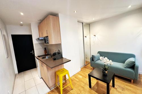 un salon avec un canapé bleu et une cuisine dans l'établissement Coquet petit Studio Hyper centre Lumineux avec Terrasse, à Marseille