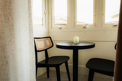 a small table and chair in a room with windows at Royale Sainte Hélène Boutique Hotel in Birkirkara