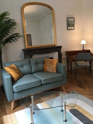 un salon avec un canapé bleu et un miroir dans l'établissement Charmant appartement ancien, lit 160, au Mans