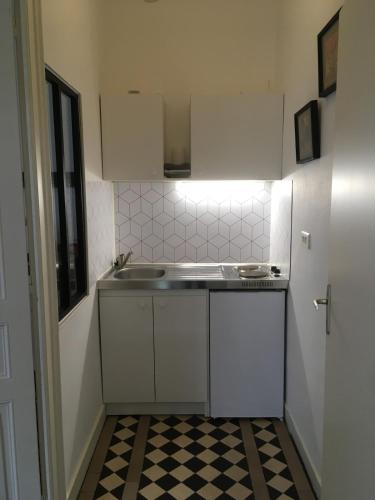 - une petite cuisine avec des placards blancs et un sol en damier dans l'établissement Charmant appartement ancien, lit 160, au Mans