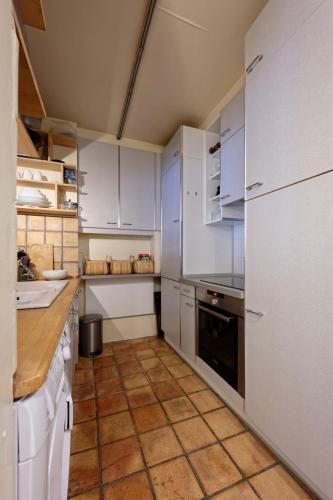 une cuisine avec des armoires blanches et un sol carrelé dans l'établissement Appartement Cosy au Coeur du marais, Paris !, à Paris