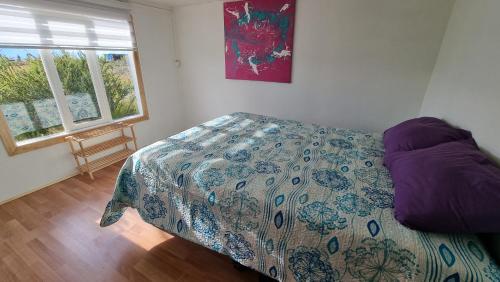 a bedroom with a bed with a comforter and a window at Cabaña Ecológica El Puesto in Puerto Natales
