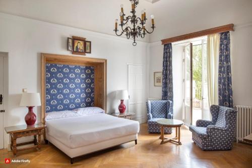 a bedroom with a bed and two chairs and a chandelier at Hospedería Santa Cruz in San Lorenzo de El Escorial