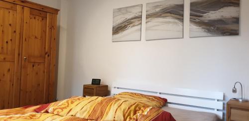 Un dormitorio con una cama con tres cuadros en la pared. en Gästehaus Siebengebirge, en Königswinter