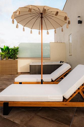 a patio with two beds and an umbrella at Royale Sainte Hélène Boutique Hotel in Birkirkara