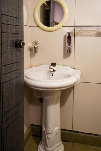 a bathroom with a white sink and a mirror at Misty Hills Cabin in Wayanad