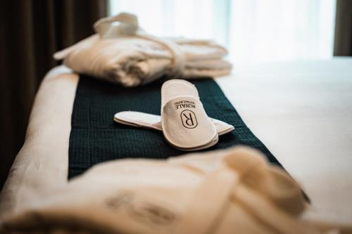 a close up of a bed with a slippers on it at Royale Sainte Hélène Boutique Hotel in Birkirkara