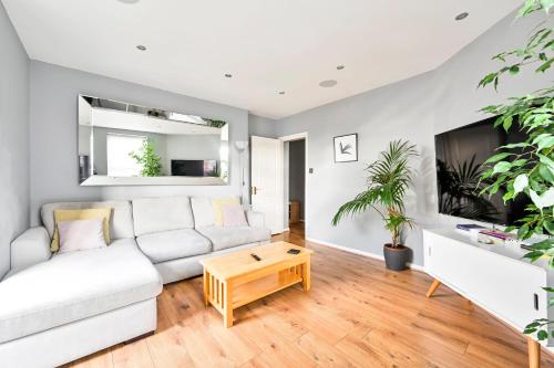 a living room with a white couch and a tv at Cosy 1-Bed E15, sleeps 4, 1 min from tube Station Near O2 Arena in London