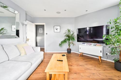 a living room with a white couch and a coffee table at Cosy 1-Bed E15, sleeps 4, 1 min from tube Station Near O2 Arena in London