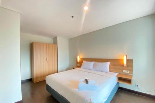 a bedroom with a large white bed with a wooden headboard at Spacious 2BR Apartment at El Royale near BIP By Travelio in Bandung