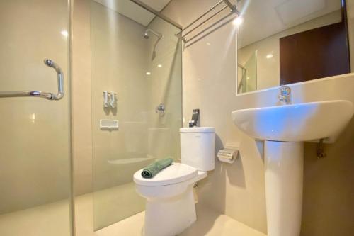 a bathroom with a toilet and a sink and a shower at Spacious 2BR Apartment at El Royale near BIP By Travelio in Bandung