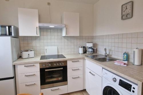 a kitchen with white cabinets and a sink and a dishwasher at Apartment Kleine Auszeit in Wiendorf