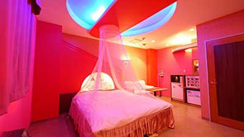 a bedroom with a bed with a red wall at Hotel Dolphin in Ishinomaki