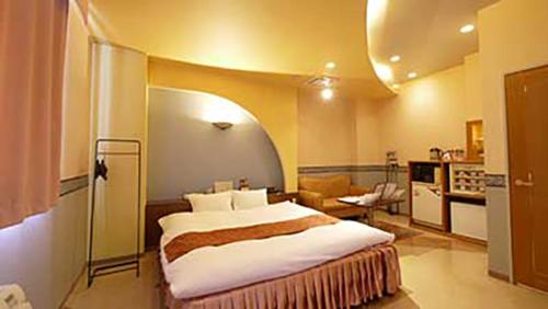 a bedroom with a large bed and a living room at Hotel Dolphin in Ishinomaki