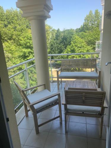2 chaises et un banc sur un balcon dans l'établissement Appartement proche mer dans résidence avec piscine, à La Baule