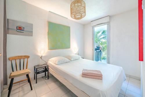 une chambre avec un lit, une chaise et une fenêtre dans l'établissement Rez de jardin à 500 m de la plage, à Cagnes-sur-Mer