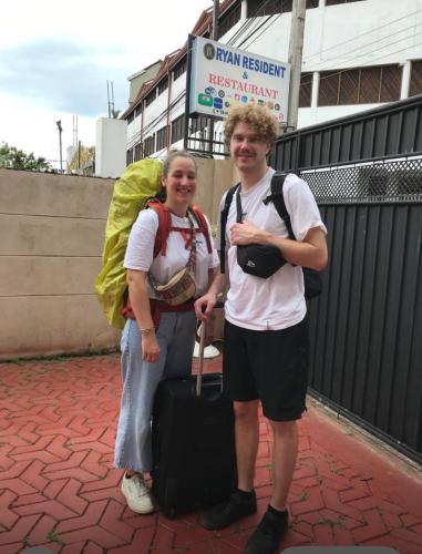 a man and woman standing on a sidewalk with a suitcase at Ryan Residence & Restaurant in Negombo