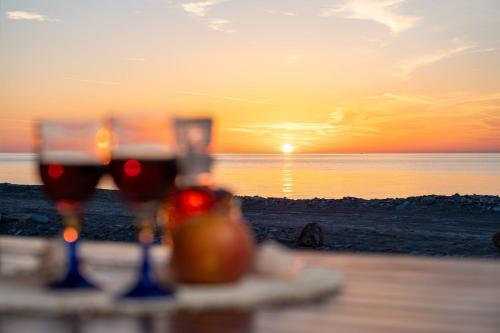 two glasses of wine on the beach with the sunset at Svala SeaView beach house in Samos