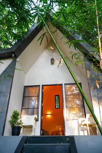 a small house with an orange door and a white chair at Misty Hills Cabin in Wayanad