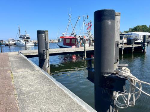 a dock with boats in the water with a rope at Gasthaus & Pension "Zur Schaabe" in Glowe