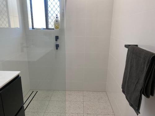 a white bathroom with a shower and a window at Kingscote Rest in Kingscote