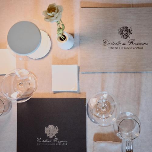 a table with two glasses of wine and a menu at Relais Castello di Razzano in Alfiano Natta