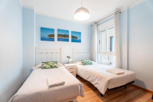 two beds in a room with blue walls at Unique Patacona in Valencia