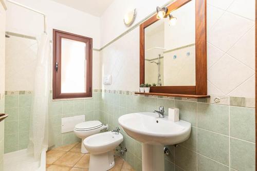 a bathroom with a sink and a toilet and a mirror at ByNos Pool - Piano Terra in Santa Maria Navarrese