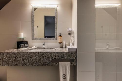 a bathroom with a sink and a mirror at Square Hotel in Kortrijk