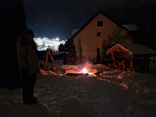 a person standing next to a fire in the snow at night at Willa Rodzinna in Tylicz