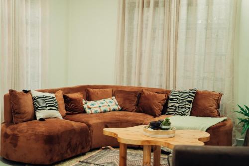a living room with a brown couch and a table at Hatua Dahlia Home in Arusha