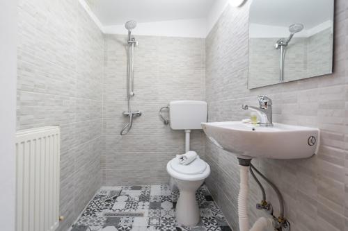 a white bathroom with a sink and a toilet at Flowers Grand Hotel Bucharest in Bucharest
