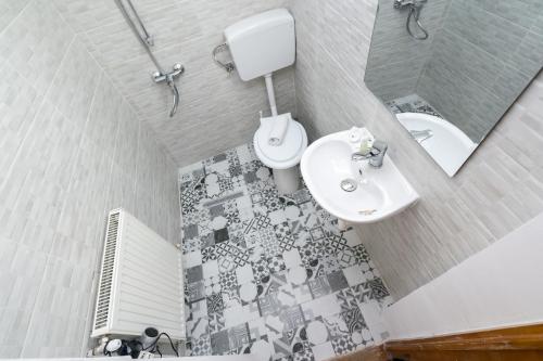 a bathroom with a white toilet and a sink at Flowers Grand Hotel Bucharest in Bucharest