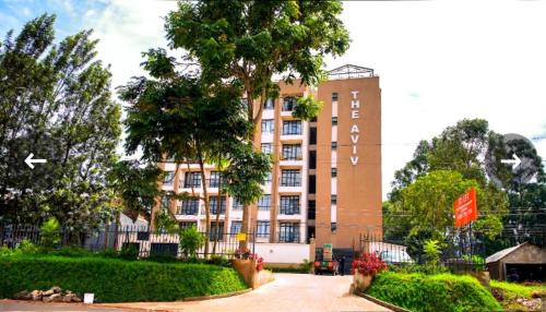 a tall building with a tree in front of it at One bedroom apartment Aviv in Nairobi