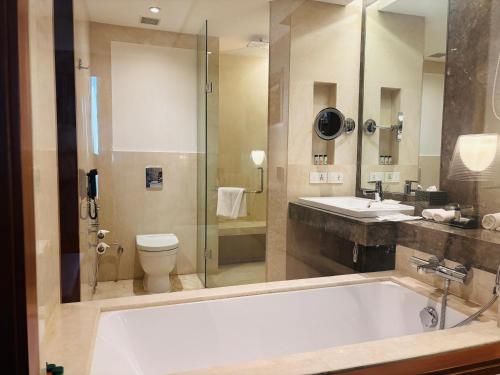 a bathroom with a tub and a sink and a toilet at The Anya Hotel-Golf Course Road in Gurgaon