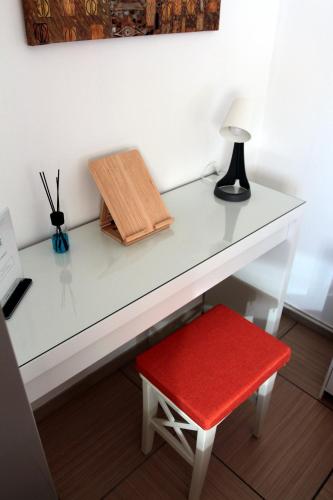 a white desk with a red stool and a lamp at Oasi Brembate Bed and Breakfast in Brembate