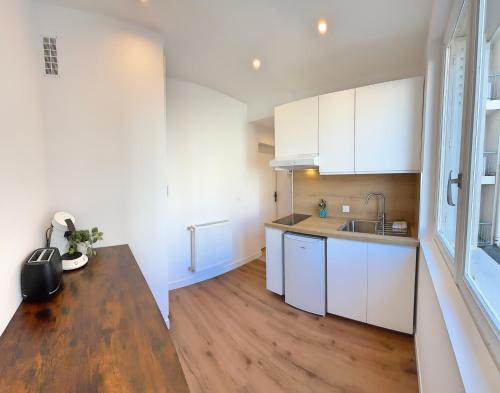 une cuisine avec des armoires blanches et une table en bois dans l'établissement Compans - Calme, à Toulouse