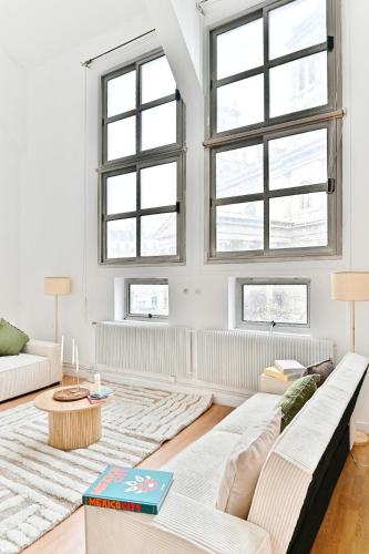 un salon avec un canapé et deux fenêtres dans l'établissement Charming very spacious apartment, Paris 9ème, à Paris