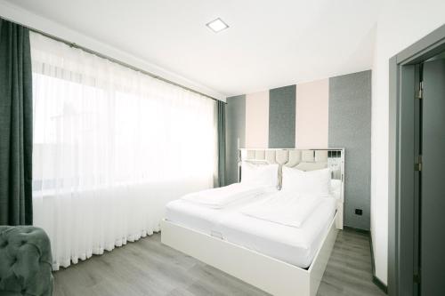 a white bed in a room with a window at PARKHOTEL BRAUNAU - 24 Stunden Self Check-IN in Braunau am Inn