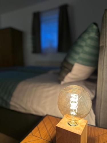 a glass object on a wooden table in front of a bed at Koralpen Appartement in Rieding